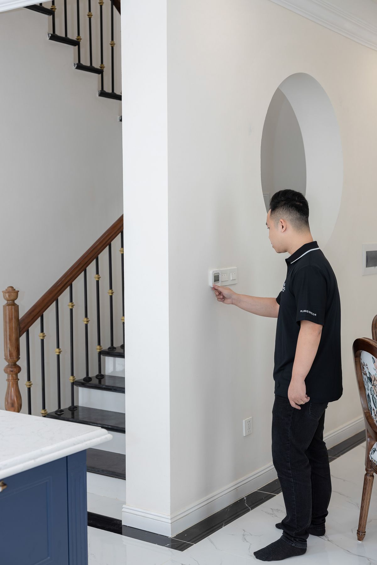 Homeowner adjusting a wall thermostat for heating service in Glastonbury CT -- Express Home Services
