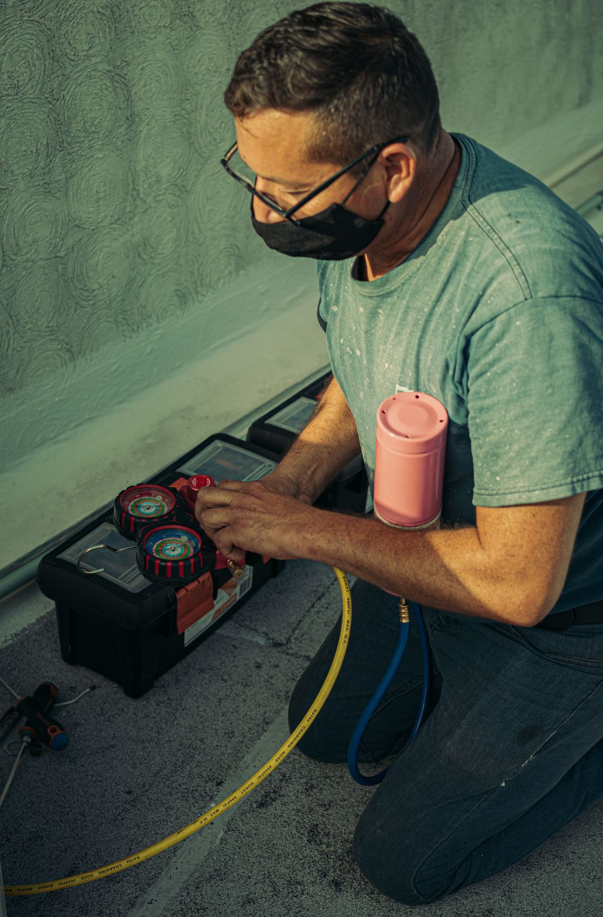 HVAC technician kneeling to perform outdoor AC maintenance in Meriden CT -- Express Home Services