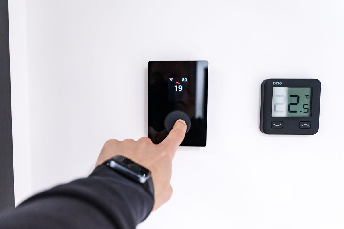 Hand adjusting a digital smart thermostat in a Norwalk CT home -- Express Home Services heating service